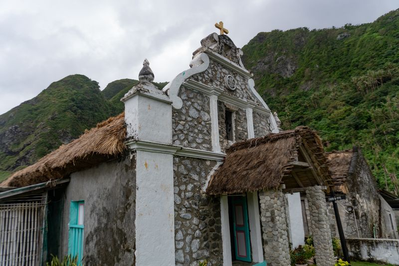 Santa Rosa de Lima Chapel in Chavayan. Note the integration of the kugon roofing, and the cobblestone masonry of its facade. What seems to be a version of the Dominican Cross (the circular emblem) can also be seen.