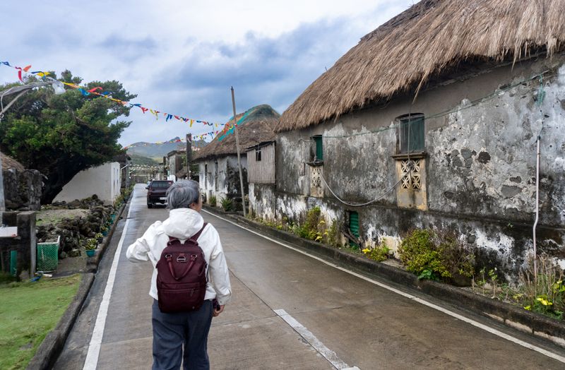 Entering the Savidug barrio. The kugon-roofed houses are actively in use; and a fiesta was just held a day or two prior (hence the banderitas). Note the pickup truck—arguably one of the rarest sights in Sabtang.