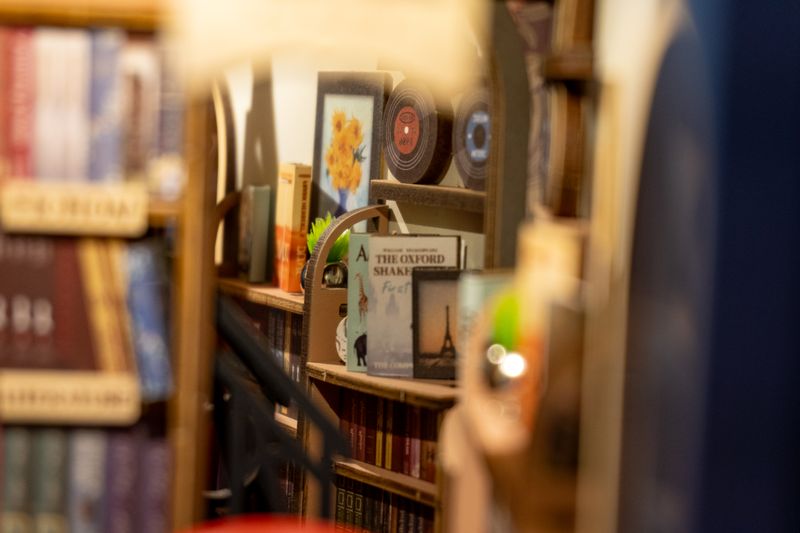 The mirror at the back simulating more space. The real stickers for the books are mirrored, achieving the effect that they're "real" beyond the mirror.